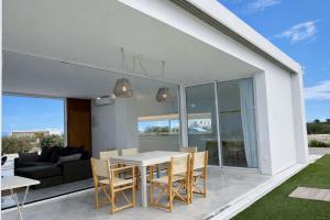 a dining room and living room with a table and chairs at Villa Codolar in Cala Morell