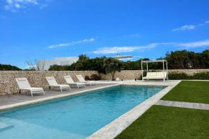 a swimming pool with lounge chairs next to a stone wall at Villa Codolar in Cala Morell