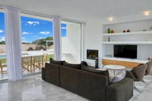 a living room with a couch and a television at Villa Codolar in Cala Morell