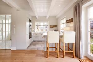 a kitchen with white cabinets and a table and chairs at Wiesen Engel in Oldsum