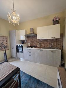 a large kitchen with white cabinets and a chandelier at Appartamento Dancardi in Quartu SantʼElena +14 photos