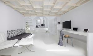a white living room with a couch and a tv at Cloud 9 in Imerovigli