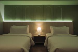 two beds in a hotel room with a lamp between them at Hotel Holm Bangkok in Bangkok