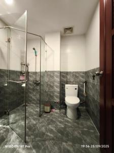 a bathroom with a toilet and a glass shower at Long Homestay Phuc An in Ðức Hòa