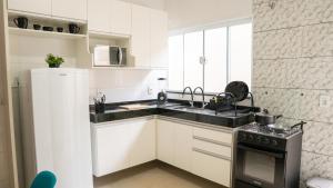 a white kitchen with a sink and a refrigerator at Jahu Center Casas Un 6 in Jaú