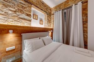 a bedroom with a white bed and a brick wall at Stone&Light in Ermoupoli