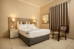 a hotel room with a bed and a chair at Tudor House Hotel in Durban