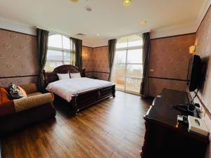 a bedroom with a bed and a television and a couch at Huis Ten Bosch in Ren'ai