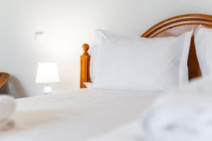 a bedroom with a bed with white pillows and a lamp at GuestReady - Funchal Hideaway with BBQ in Funchal +24 photos