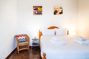 a bedroom with a large white bed with a chair at GuestReady - Funchal Hideaway with BBQ in Funchal