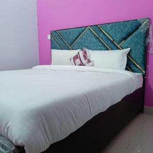 a large bed with white pillows and pink walls at AG Hotel in Zirakpur