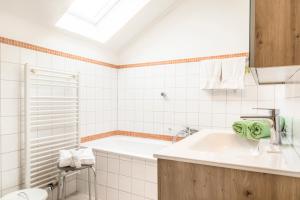a white bathroom with a tub and a sink at Bambichl Hoamat in Fuschl am See +19 photos