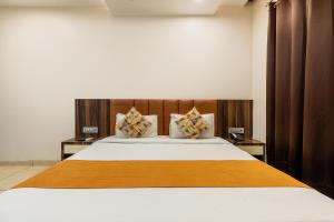 a bedroom with a large bed with a wooden headboard at FabHotel Prime The Bentree in Bhopal