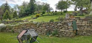 a stone wall and a chair in a field at Hvězda in Želnava