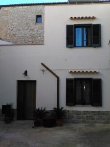 a white building with black windows and a door at L'Azzurro Apartment in Valderice