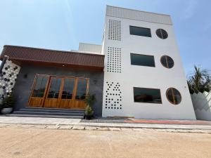 a white building with a wooden door on a street at S77 Good View in Roi Et