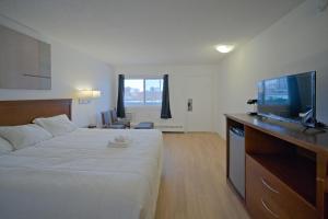 a hotel room with a bed and a flat screen tv at MXP Special Rooms in Saskatoon