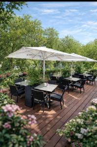a wooden deck with tables and a white umbrella at Hotel am Westend in Lahr