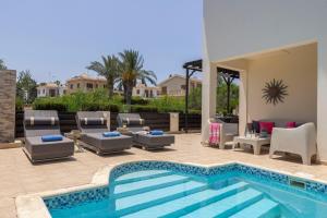 a pool with chaise lounge chairs and a swimming pool at Villa Mesogeios 39 in Paralimni