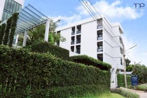 a white building with a hedge in front of it at Tassana Place in Chon Buri