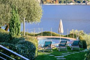 two chairs and an umbrella next to a swimming pool at Villa Costanza- private heated pool, steam room & sauna - Bellagio Village Residence in Oliveto Lario