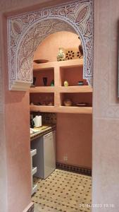 a kitchen with an arched doorway into a kitchen with a stove at Riad Fadela in El Jadida