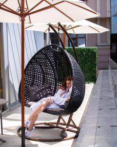 a woman sitting in a wicker chair under an umbrella at Wall Street - Maestro in Odesa