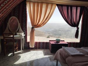 a bedroom with a large window with a view at Mujib Castle Gate Camp in Dhībān