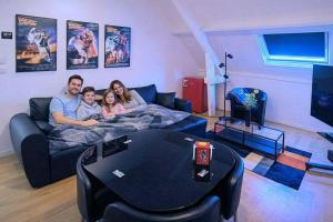 a family laying on a couch in a living room at Fitness loft 50 m2 in Zemst