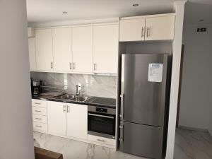 eine Küche mit weißen Schränken und einem Edelstahlkühlschrank in der Unterkunft Plomari View Stone Apartments in Plomari