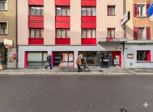 people walking down a street in front of a building at Hotel Rothaus Luzern & Peruvian Culinary Art in Lucerne