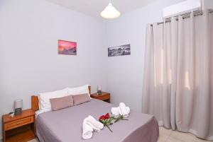 a bedroom with a bed with towels and flowers on it at Efrosini & Ioanna Apartment in Ligaria