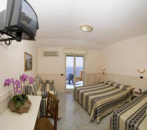 a hotel room with two beds and a flat screen tv at Hotel Klein Wien in Piano di Sorrento