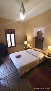 a bedroom with a large white bed and a chandelier at Riad Fadela in El Jadida