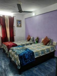 two beds in a room with purple walls at Hotel Ashu , Ntl Road in Haldwāni