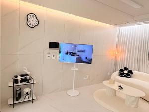 a white living room with a tv on a wall at 해변1분 숙소 광안이즘, 1 min to beach Gwangan-ism in Kwangan-dong