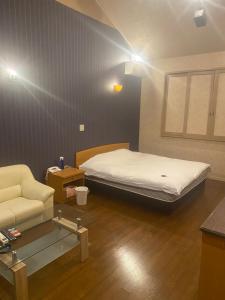 a bedroom with a bed and a couch in it at ホテルラブリー淡路島 in Sumoto