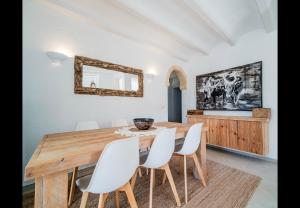 a dining room with a wooden table and white chairs at La Finca Blanca Javea in El Tosalet