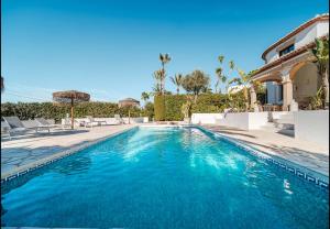 a swimming pool in front of a house at La Finca Blanca Javea in El Tosalet