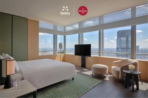 a hotel room with a bed and a tv and windows at Park Hyatt Changsha in Changsha