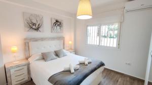 a bedroom with a white bed and two windows at La Terraza de María P in Torre del Mar