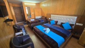 a hotel room with two beds and a chair at Sleeping Beauty Hotel Moutain view property in Joshīmath