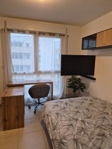 a bedroom with a bed and a desk with a monitor at Studio avec parking privé - Proche écoles & hôpital - Valence in Valence