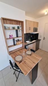 a kitchen with a wooden table with two plates on it at Studio avec parking privé - Proche écoles & hôpital - Valence in Valence