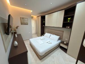 a bedroom with a white bed and a television at Onis Apartment in Vlorë