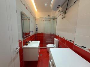a red bathroom with a toilet and a sink at Onis Apartment in Vlorë +7 photos