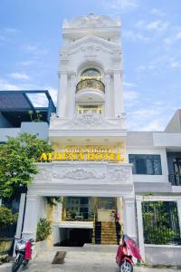 a white building with a hotel with motorcycles parked in front at Athena Hotel Huế in Hue