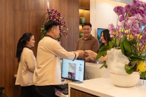 a man shaking another mans hand at a counter in a salon at TROY HOTEL - Bà Rịa in Ấp Long Kiên I