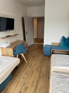 a room with two beds and a table and a tv at Gasthaus - Hotel Neue Post in Meitingen