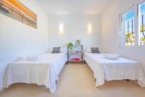two beds in a room with white walls at Villa Kuki - PlusHolidays in Ifach +58 photos
